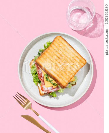 Club sandwich of toast bread with bacon, cheese, tomatoes, lettuce, arugula and sauce in a plate 130561080