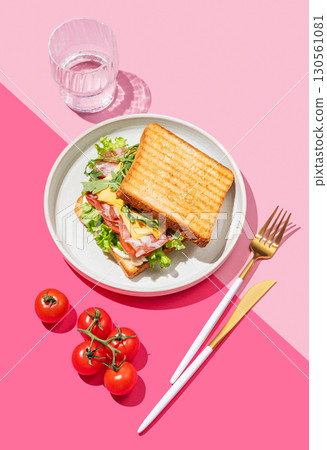 Club sandwich of toast bread with bacon, cheese, tomatoes, lettuce, arugula and sauce in a plate 130561081