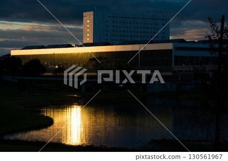 Buildings and water surface reflecting the setting sun 130561967