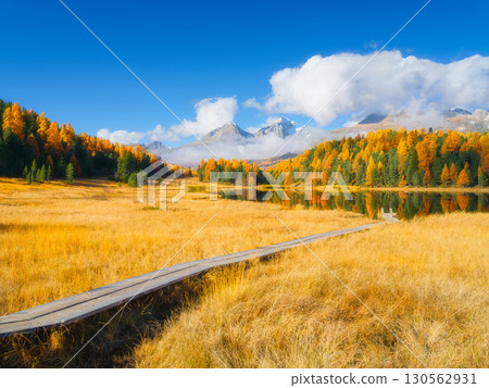 Lake and a small pier. Autumn landscape in Switzerland. Clouds and fall forest. Lake and a small pier. Autumn landscape in Switzerland. Clouds and fall forest. 130562931