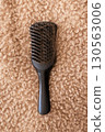 Black hairbrush with fallen hair on a fluffy beige background. Hair loss, shedding 130563006