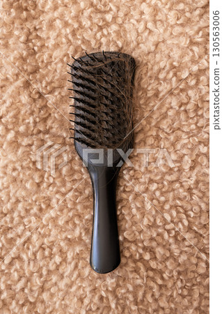 Black hairbrush with fallen hair on a fluffy beige background. Hair loss, shedding 130563006