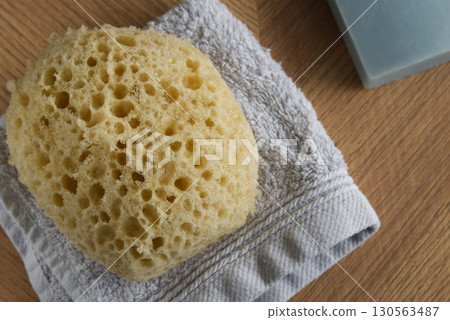 Dermo Aqua soft bath sponge on a wooden background 130563487