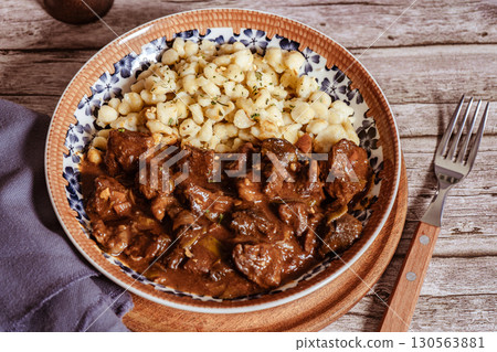 Delicious hungarian goulash with spaetzle on rustic wooden table Delicious hungarian goulash with spaetzle on rustic wooden table 130563881