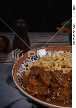 Delicious hungarian goulash with spaetzle resting on rustic table Delicious hungarian goulash with spaetzle resting on rustic table 130563889