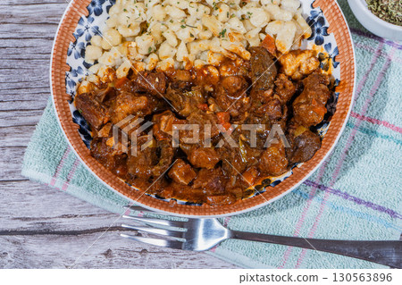 Delicious hungarian goulash with spaetzle on rustic wooden table 130563896