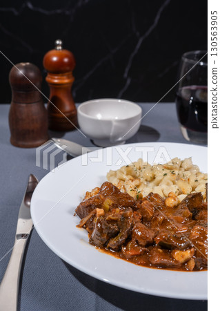 Delicious hungarian goulash with spaetzle, a traditional stew, served on a white plate 130563905