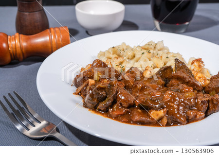 Delicious hungarian goulash with spaetzle served on white plate Delicious hungarian goulash with spaetzle served on white plate 130563906