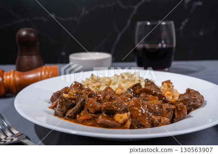 Delicious hungarian goulash with spaetzle accompanying red wine Delicious hungarian goulash with spaetzle accompanying red wine 130563907
