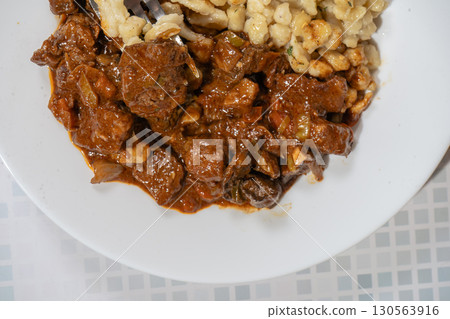 Fork lifting spaetzle from plate of beef goulash stew 130563916