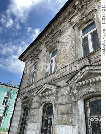 Ornate historic building facade against blue sky with clouds, suitable for architectural background Ornate historic building facade against blue sky with clouds, suitable for architectural background 130564213