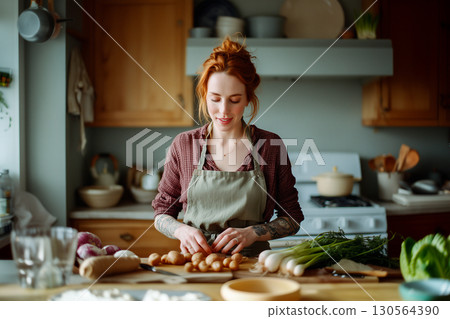 A woman is cooking in a kitchen with a green apron on 130564390
