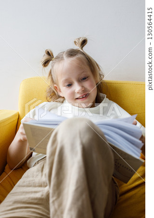 Happy little child girl reading book at home, indoor portrait 130564415