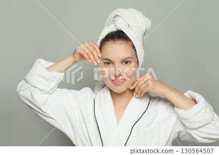 Smiling young woman with moisturizing, rejuvenating white fabric sheet mask from her face  130564507
