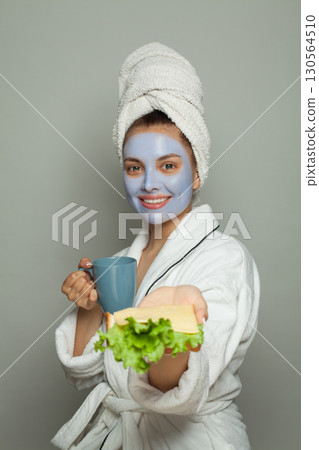 Breakfast and morning routine. Cute woman with cosmetic facial mask Breakfast and morning routine. Cute woman with cosmetic facial mask 130564510