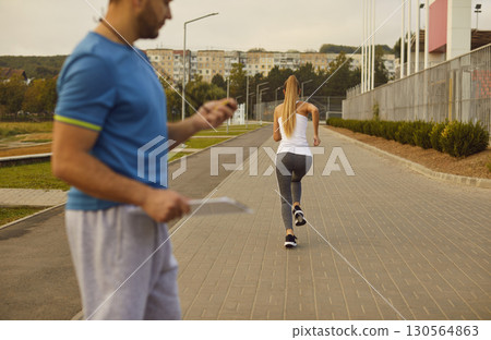 Coach Timing Woman During Outdoor Running Training In City Park 130564863