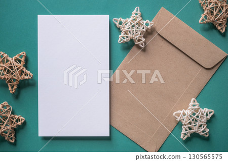 White blank greeting or invitation card and envelope with Christmas decoration on green background. White blank greeting or invitation card and envelope with Christmas decoration on green background. 130565575