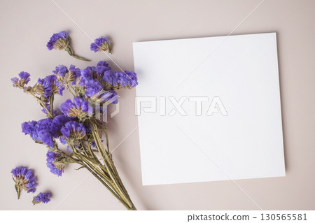 White blank greeting or invitation card with purple flower decoration on beige background. White blank greeting or invitation card with purple flower decoration on beige background. 130565581