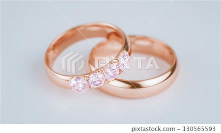 A close-up of a pair of rose gold wedding rings adorned with sparkling pink diamonds, pledging eternal love between two people. 130565593