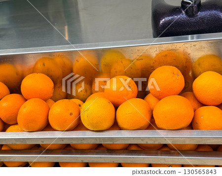 A row of fresh oranges stacked inside a metal container. Freshness, nutrition, and food display in daily market. 130565843