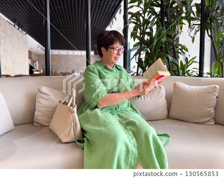Woman in glasses smiling while holding book. Happiness, reading, and intellectual lifestyle. Woman in glasses smiling while holding book. Happiness, reading, and intellectual lifestyle. 130565853