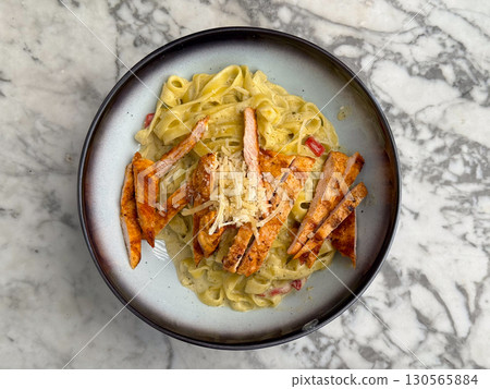 Tagliatelle pasta with grilled chicken and parmesan in creamy sauce. Cuisine, flavor, and gourmet dining in restaurant lifestyle and food culture. 130565884