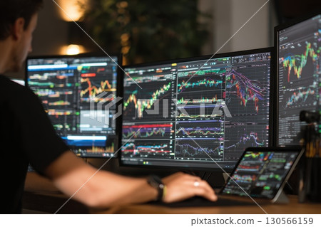 Financial Analyst Working with Multiple Monitors for Market Data and Stock Monitoring Analysis 130566159