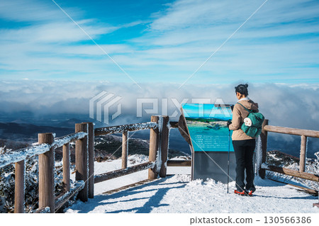 Female hiker reading signboard on Eorimok Trail, Hallasan, Jeju in winter Female hiker reading signboard on Eorimok Trail, Hallasan, Jeju in winter 130566386