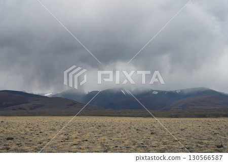 Thunderclouds and rain coming from snowy mountains over the steppe 130566587