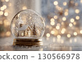 glass snow globe containing a miniature snowy house and pine trees 130566978