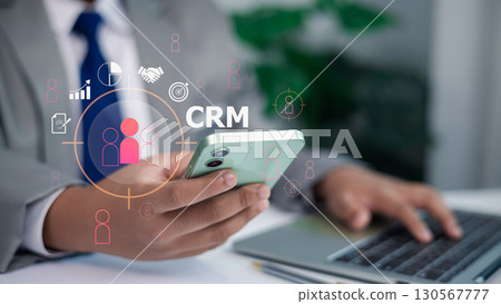 Business Person Holding Smartphone with CRM Icons Digital Overlay for Customer Relationship Management Business Person Holding Smartphone with CRM Icons Digital Overlay for Customer Relationship Management 130567777
