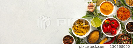A mix of dried herbs and spices laid out on a gray background, highlighting natural flavors and culinary essentials, top view and copy space, banner 130568000