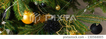 Sophisticated gold and black-toned gift boxes paired with glowing candles and intricate ornaments, nestled under the Christmas tree for a warm and modern holiday celebration, banner Sophisticated gold and black-toned gift boxes paired with glowing candles and intricate ornaments, nestled under the Christmas tree for a warm and modern holiday celebration, banner 130568005