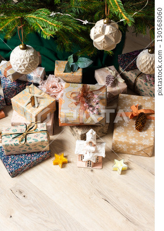 A cozy Christmas scene with elegant natural-toned gift boxes placed under a Christmas tree, lit with festive lights, evoking peace and seasonal joy A cozy Christmas scene with elegant natural-toned gift boxes placed under a Christmas tree, lit with festive lights, evoking peace and seasonal joy 130568060