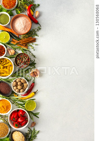 Various cooking spices and herbs spread across a neutral gray background, showcasing their rich, natural tones, top view and copy space 130568068
