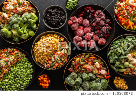 A variety of frozen vegetables and fruits arranged in plates, set against a dark background, capturing the essence of summer preservation for winter meals A variety of frozen vegetables and fruits arranged in plates, set against a dark background, capturing the essence of summer preservation for winter meals 130568078