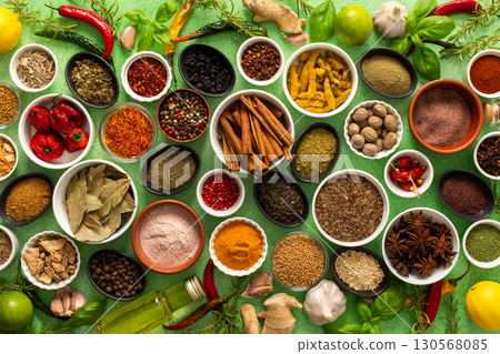 A colorful assortment of fresh, fragrant spices and herbs displayed on a soft green background, capturing a vibrant culinary essence 130568085