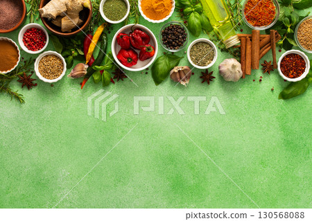A vibrant assortment of fresh, multicolored spices and herbs on a delicate green background, perfect for cooking and culinary inspiration, top view and copy space 130568088