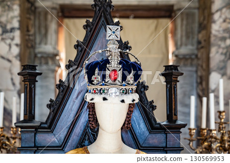 Mannequins in an ornate hall showcase embroidered gowns with pearls and feathered headpieces, reflecting regal ceremonial fashion. Mannequins in an ornate hall showcase embroidered gowns with pearls and feathered headpieces, reflecting regal ceremonial fashion. 130569953