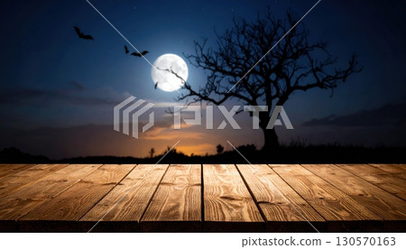 An eerie Halloween night with a silhouette of trees against an orange sky and a full moon 130570163