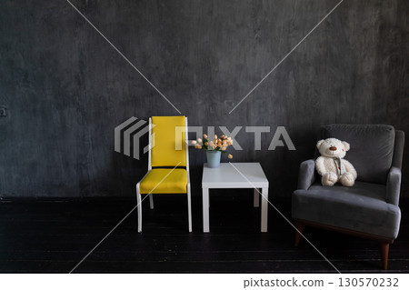 armchair and table with vase of flowers in dark gray room interior 130570232
