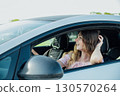 Excited young woman driving vehicle confidently, 130570264