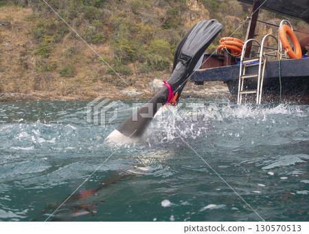 A woman's foot in the fins of a diver diving into the sea near a tropical island 130570513