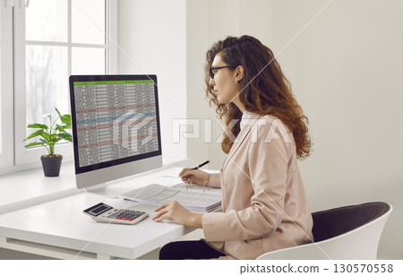 Businesswoman analyzing financial data on computer screen in office Businesswoman analyzing financial data on computer screen in office 130570558
