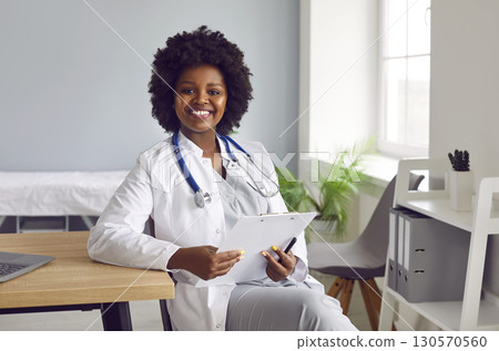 Portrait of a young african american doctor in white medical uniform looking at the camera. Portrait of a young african american doctor in white medical uniform looking at the camera. 130570560