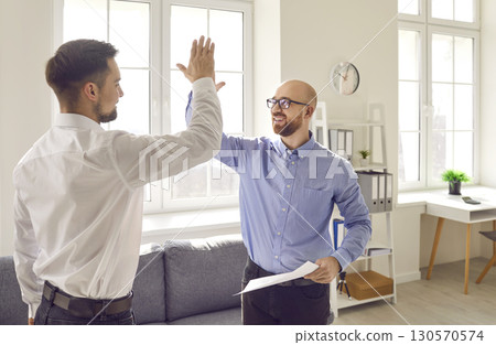 Two happy young men make a successful business deal and give each other a high five 130570574