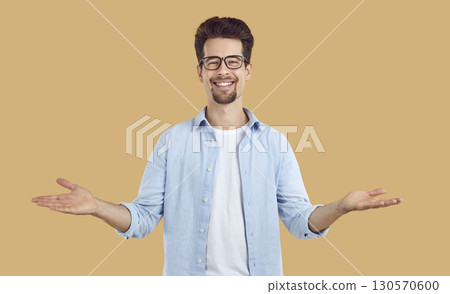 Happy man in glasses inviting you to educational lecture and doing welcoming gesture 130570600