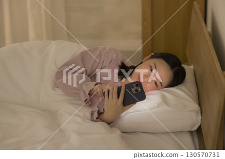 一名婦女在床上的看一個智能手機 130570731