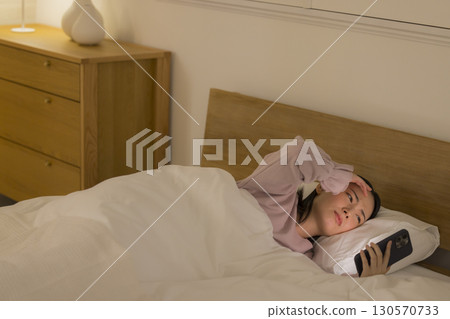 A woman watching a smartphone in bed A woman watching a smartphone in bed 130570733