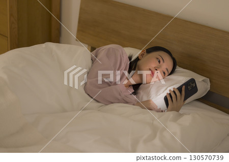 A woman watching a smartphone in bed 130570739